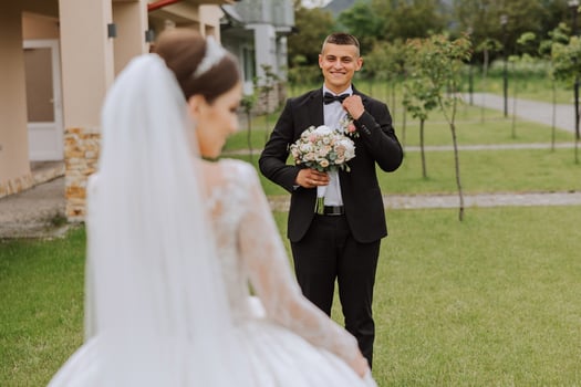 A beautiful young bride in a summer park is walking to her groom. Photo of the bride from behind. Beautiful wedding white dress. Walks in the park. A happy and loving couple.