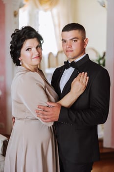 mother helps her adult son prepare for the wedding ceremony. An emotional and touching moment at a wedding. A mother hugs her son photo