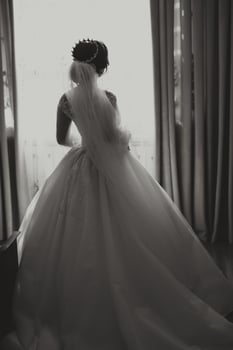 A luxurious bride with a beautiful hairstyle and a chic dress, back view, is getting ready for the wedding ceremony in the morning. Morning photo of the bride at home or in a hotel room.