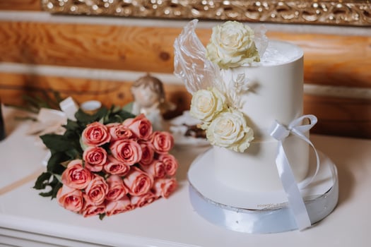 A large luxurious multi-tiered wedding cake is decorated with fresh white rose flowers in the banquet hall. Wedding dessert under the evening light. Wedding decor. photo