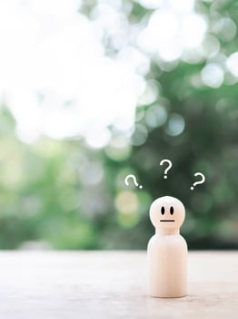 Wooden human figure with question marks. The concept of question or answer time. photo