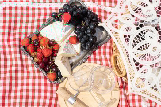 summer picnic on a green lawn with red wine, cheese and fresh berries, grapes photo