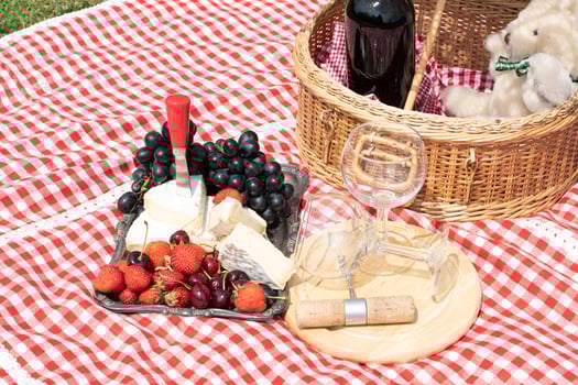 summer picnic on a green lawn with red wine, cheese and fresh berries, grapes photo