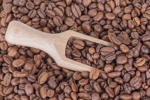 Wooden spoon with coffee and roasted coffee beans on the background. Coffee as background. photo