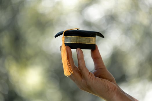 Hand holding graduation cap. concept for education and scholarship, student loan, study financial, save money for a degree, saving for education photo