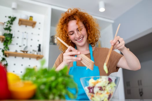 Beautiful cute young smiling woman on the kitchen is preparing a vegan salad in casual clothes. photo