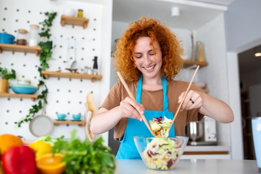 Beautiful cute young smiling woman on the kitchen is preparing a vegan salad in casual clothes. photo