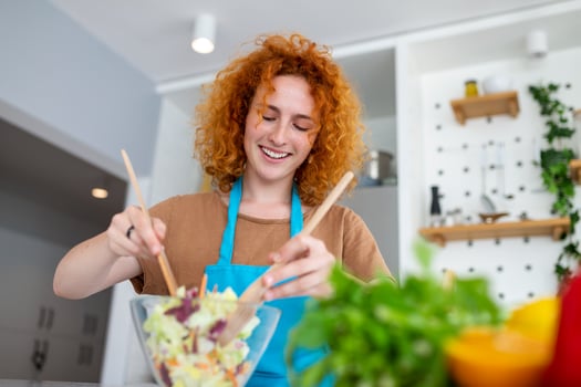 Beautiful cute young smiling woman on the kitchen is preparing a vegan salad in casual clothes. photo