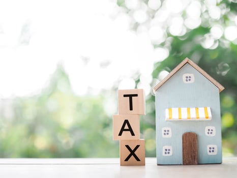 Miniature house and Wooden blocks with the word TAX. The concept of payment tax for house, Property investment, House mortgage, Real estate photo