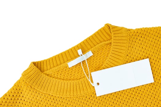 White blank rectangular clothing tag on yellow knitted sweater isolated on white background photo