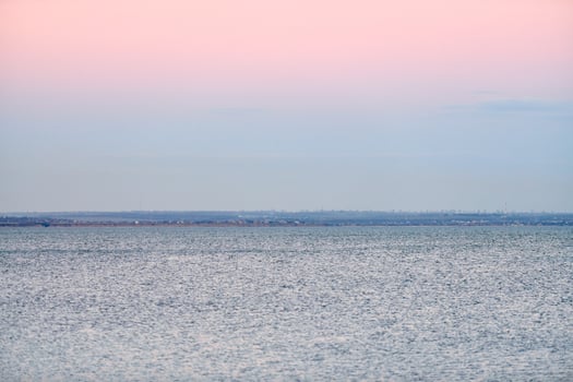 Atmospheric romantic pink red sea sunset sky above blue quiet water, minimalistic peaceful seascape photo