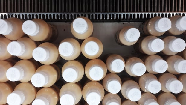 bottles with white caps are lined up in supermarket display cases photo