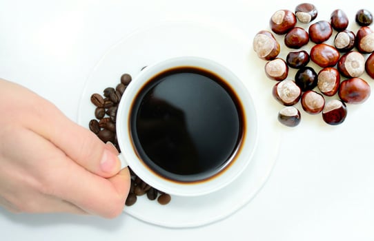 cup of coffee and nuts with hand holding cup photo