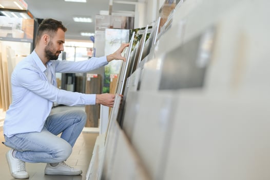 Young man choosing tiles at building market photo