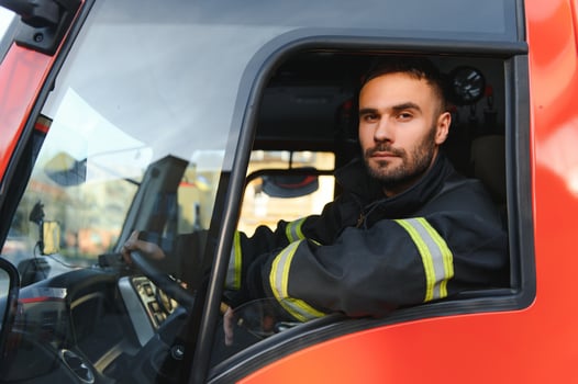Side view of firefighter in protective uniform driving fire engine photo