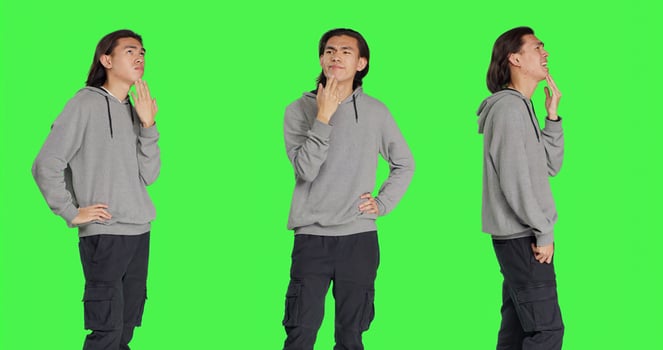 Asian man questioning perspective standing in greenscreen studio, thinking about answer and pondering. Male model in a dilemma trying to focus, pensive uncertain young adult thinker. photo