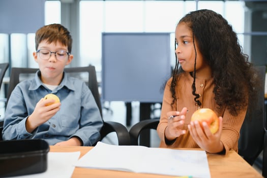 Multiracial schoolchildren having lunch at the desk during a break in school photo