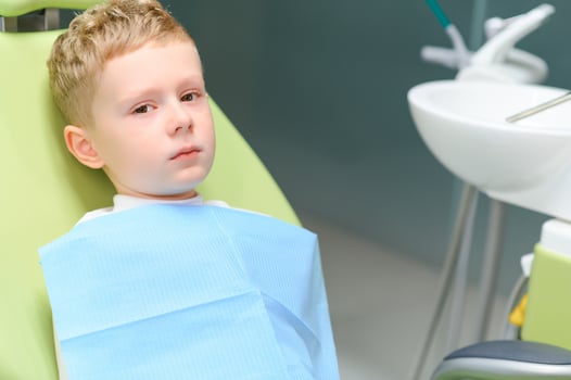 Scared red-haired boy crying at reception at dentist in dental chair. Pediatric dentistry photo