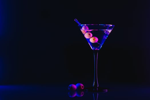 Martini cocktail drink splash with ice cubes in neon iridescent pink and blue colors. Minimal night party life concept. photo