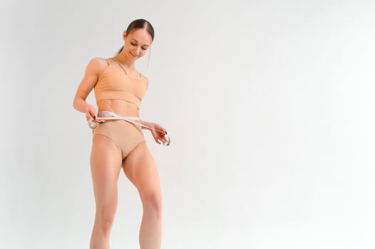 Woman measuring her slim body isolated on white background. photo