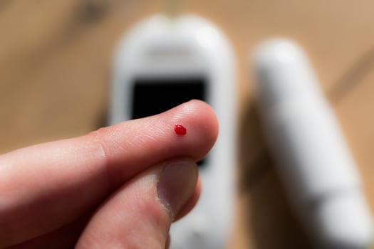 Woman pricking her finger to check blood glucose level with glucometer, test blood glucose for diabetes photo