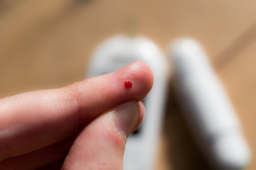 Woman pricking her finger to check blood glucose level with glucometer, test blood glucose for diabetes photo