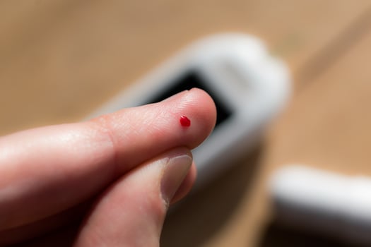 Woman pricking her finger to check blood glucose level with glucometer, test blood glucose for diabetes photo