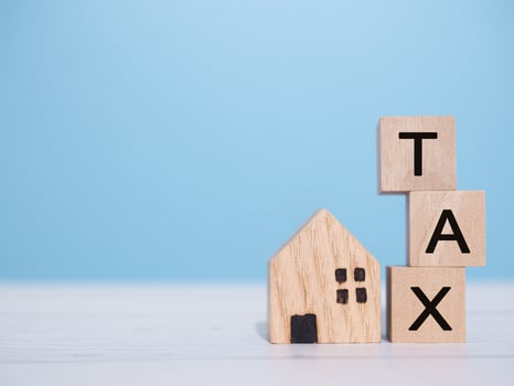 Miniature house and Wooden blocks with the word TAX. The concept of payment tax for house, Property investment, House mortgage, Real estate photo