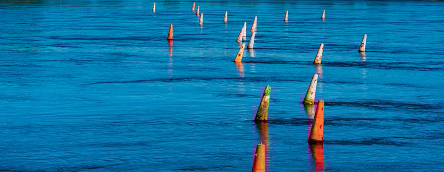river barrier made of old faded orange buoys photo