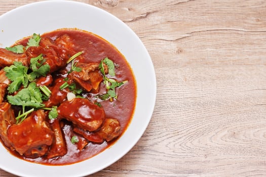Chinese Red Soup Pork Ribs served on a white plate, a popular Chinese dish, made from sliced pork ribs and tomato sauce. photo