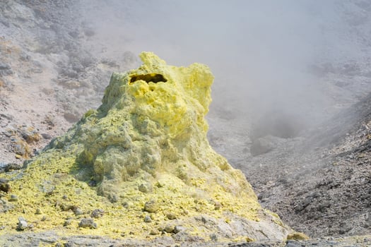 tower of crystallized sulfur around a fumarole on the slope of a volcano photo