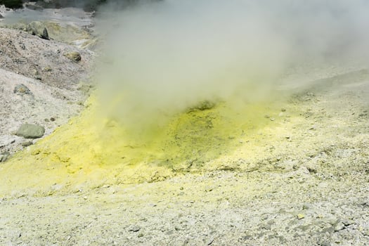 smoking solfatara among sulfur deposits on the slope of the volcano photo