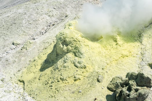 yellow cone of crystallized sulfur around a smoking solfatara on the slope of a volcano photo