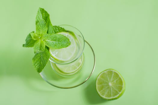 tea with mint and lime, with a calming effect, green still life close-up on a green background, top view. mojito, health drink, alternative medicine photo