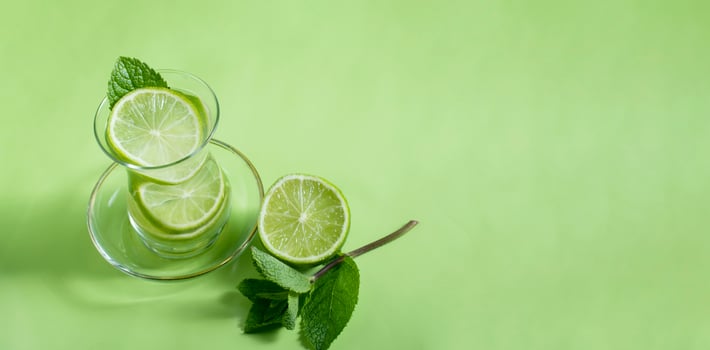 tea with mint and lime, with a calming effect, green still life close-up on a green background, top view. mojito, health drink, alternative medicine photo