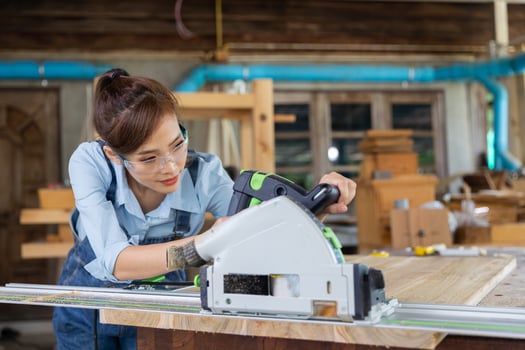 Young woman is training to be a carpenter in workshop. Carpenter working with equipment on wooden table. woman works in a carpentry shop. photo