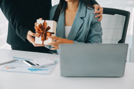 Young businessman giving his colleague present in office. Young man surprise beautiful businesswoman in office. photo