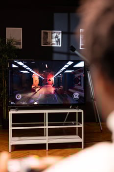 BIPOC man playing action videogames on smart TV, relaxing after long day at work. Gamer enjoying SF first person shooter game on gaming console, shooting laser bullets at enemies photo