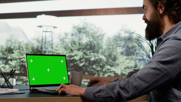 Wealthy industrialist unwinds at his elegant property in the mountains, examining greenscreen display on his laptop. Worldwide firm leader connects on PC with blank mockup screen, posh life. photo