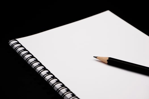 Black pencils with black spiral notebook on black background. photo
