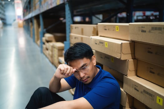 worker sits leaning against a box holding a tablet and in a warehouse. Concept of thinking about problems at work. supply chain and warehouse business concept . photo