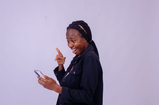 beautiful young african lady pointing to her phone screen in excitement photo