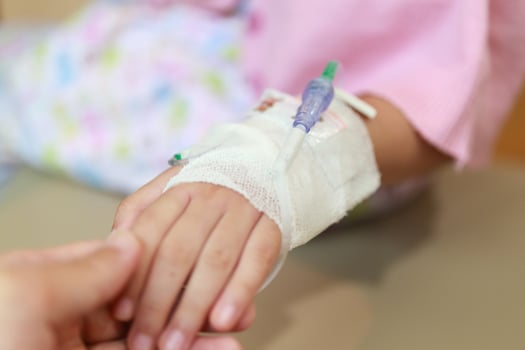 Mother holding child hand with saline IV solution in hospital photo