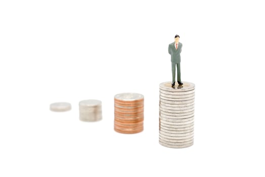Miniature businessman standing on stack of new Thai Baht coins, isolated on white background. Business and finance concept. photo