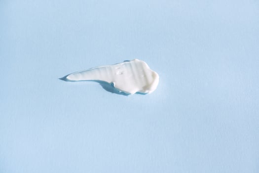 White smear of cosmetic cream on a blue background. Creamy base texture isolated. A smear of face cream. Close-up of creamy texture photo