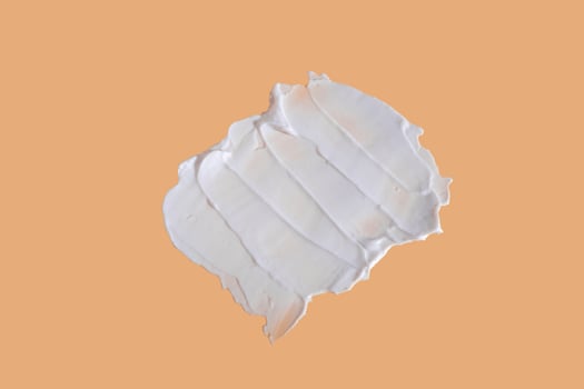 White smear of cosmetic cream on a beige background. Creamy foundation texture isolated. Smear of face cream. Close up of cream texture photo