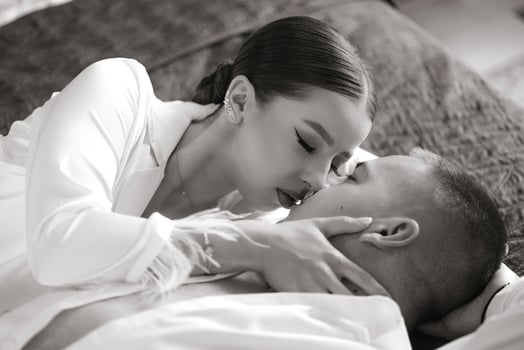 Sensual and gentle morning of the bride and groom in the hotel room. Happy and in love bride and groom are lying on the bed. Confident girl-bride and handsome groom. Preparation for the wedding photo