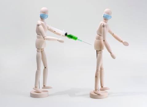 a wooden model of a human being vaccinated or injected into another person's buttock photo
