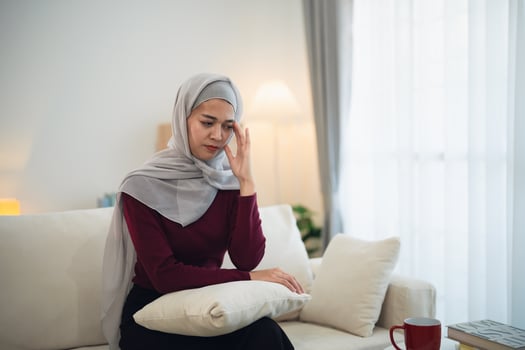 Muslim islam Asian woman wearing hijab depressed sadly serious  having stressful depression sad time sitting on sofa in the living room at home. Depression woman sad serios health mental concept. photo