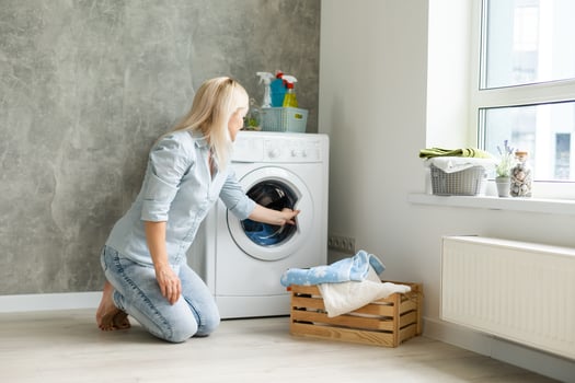 A young housewife with washing machine and clothes. Washing day. photo